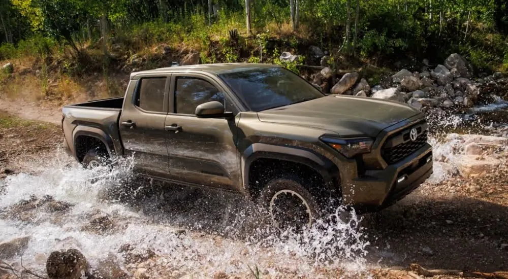 Green 2026 Toyota Tacoma crossing a stream