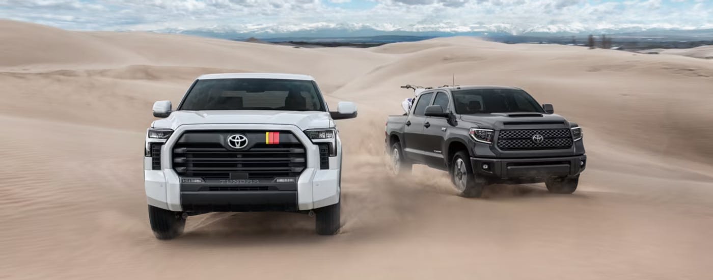 White and a black 2026 Toyota Tundra TRD Pro's driving side by side on sand