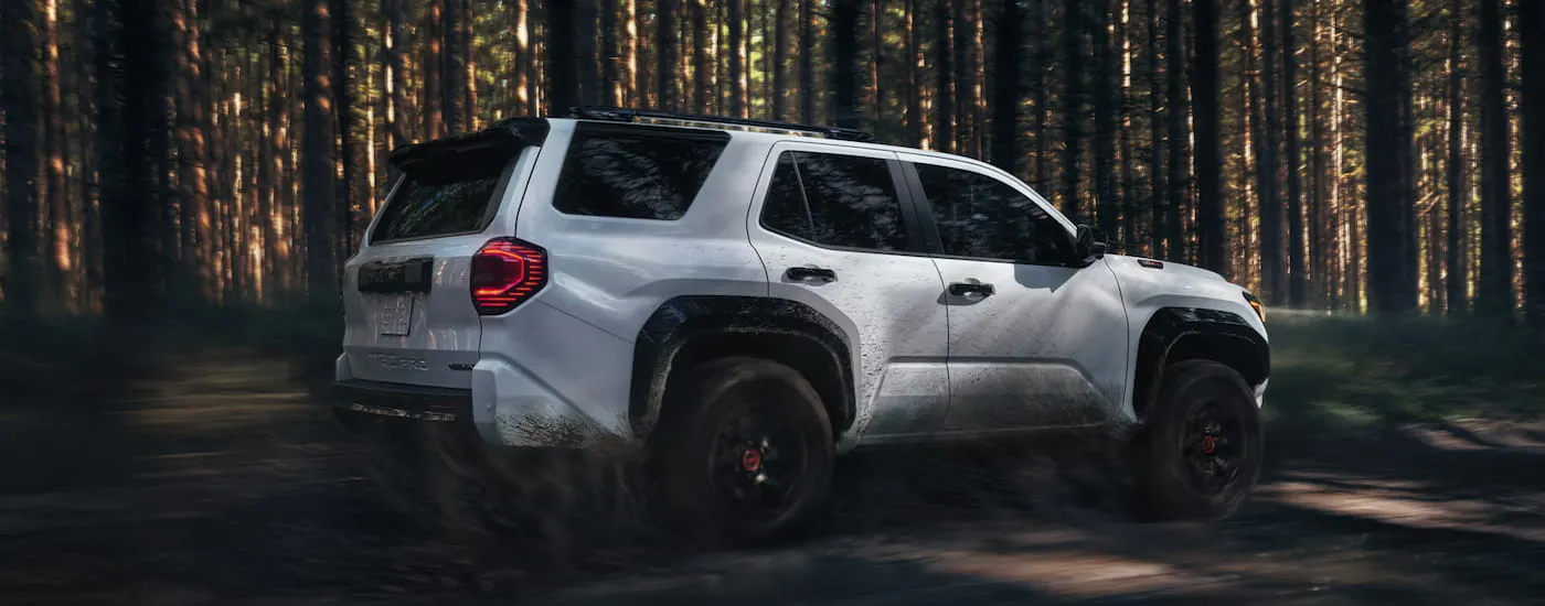 Rear of a white 2026 Toyota 4Runner driving through a forest.