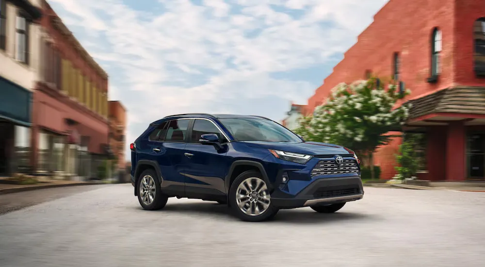Blue 2026 Toyota RAV4 driving through a town.