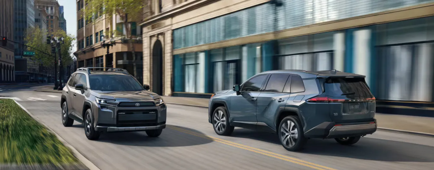 A grey 2026 Toyota RAV4 passing a blue 2026 Toyota RAV4 in a city