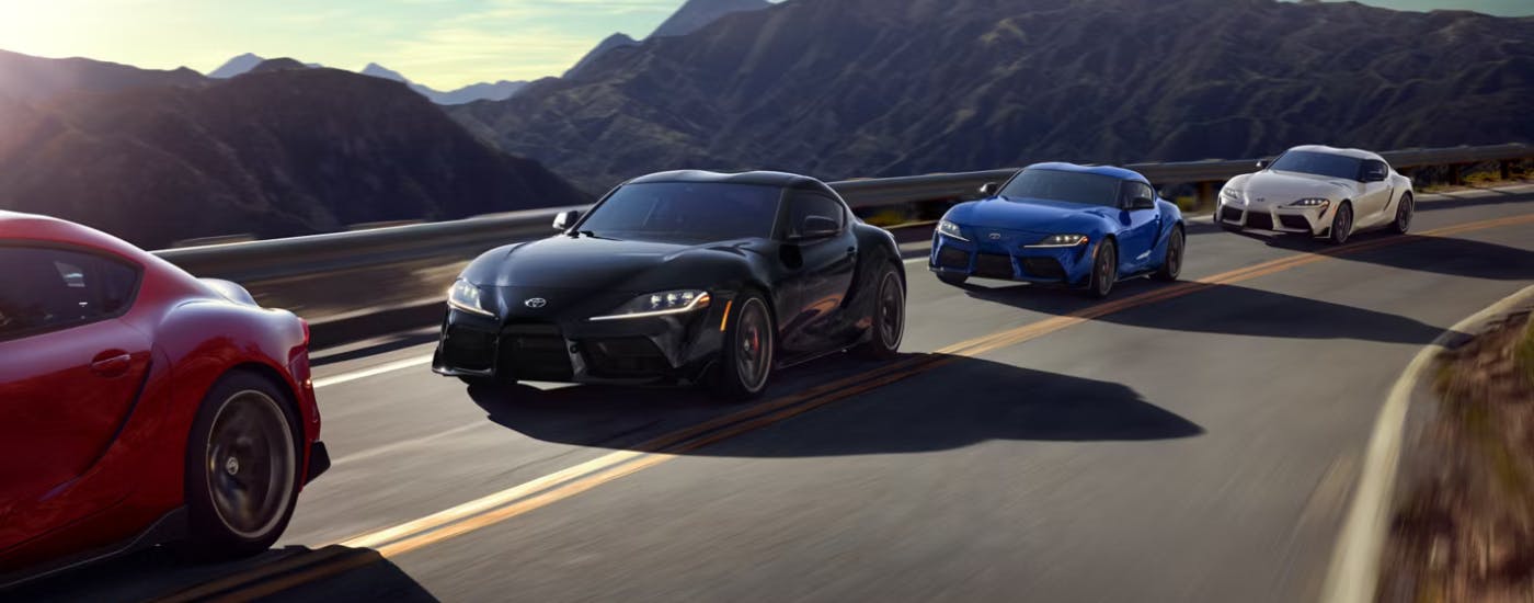 A line of 2026 Toyota Supra on a canyon road featuring a red one, a black one, a blue and a white 