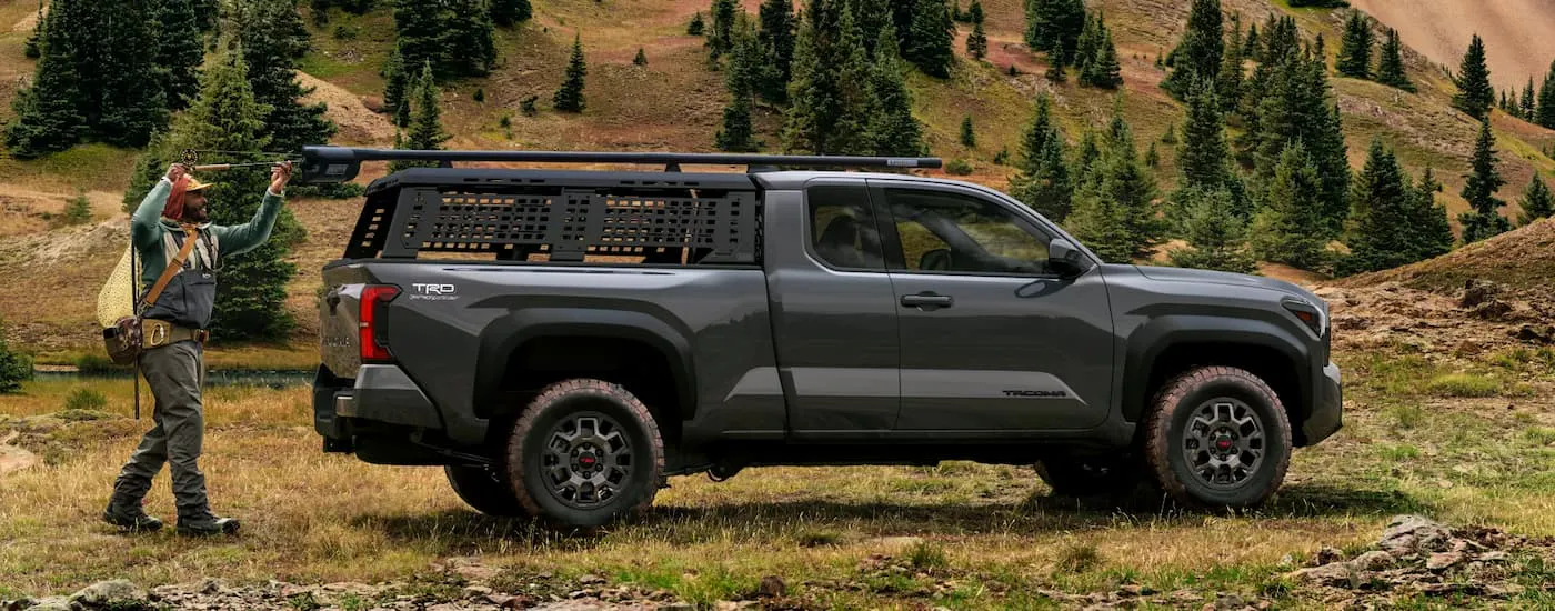 Side of a grey 2026 Toyota Tacoma TRD PreRunner parked off-road on a field.