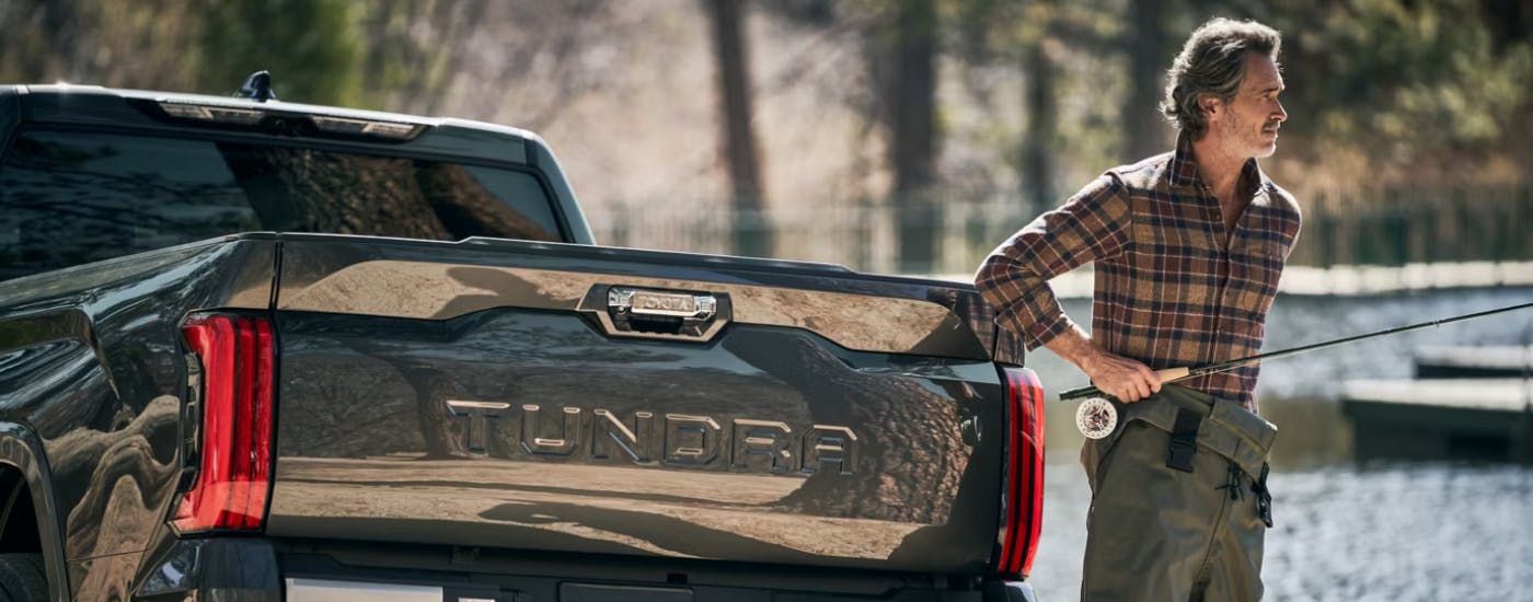 A person with a fly rod walking away from their black 2026 Toyota Tundra