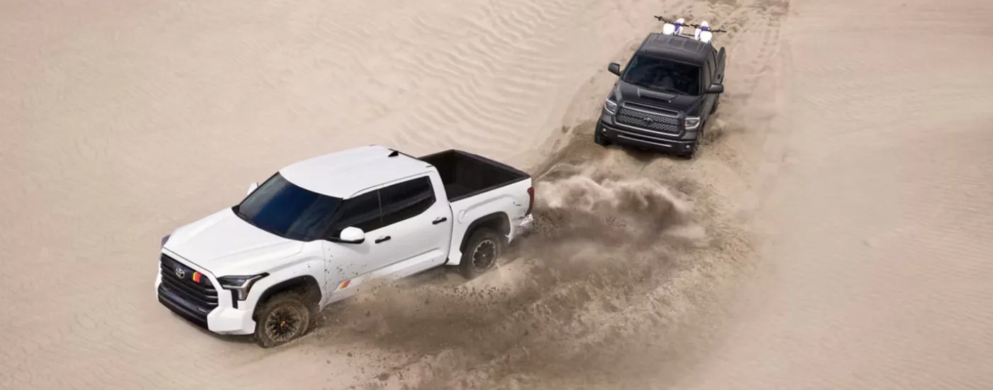 White 2026 Toyota Tundra Rally Edition diving on sand with a black 2026 Toyota Tundra following