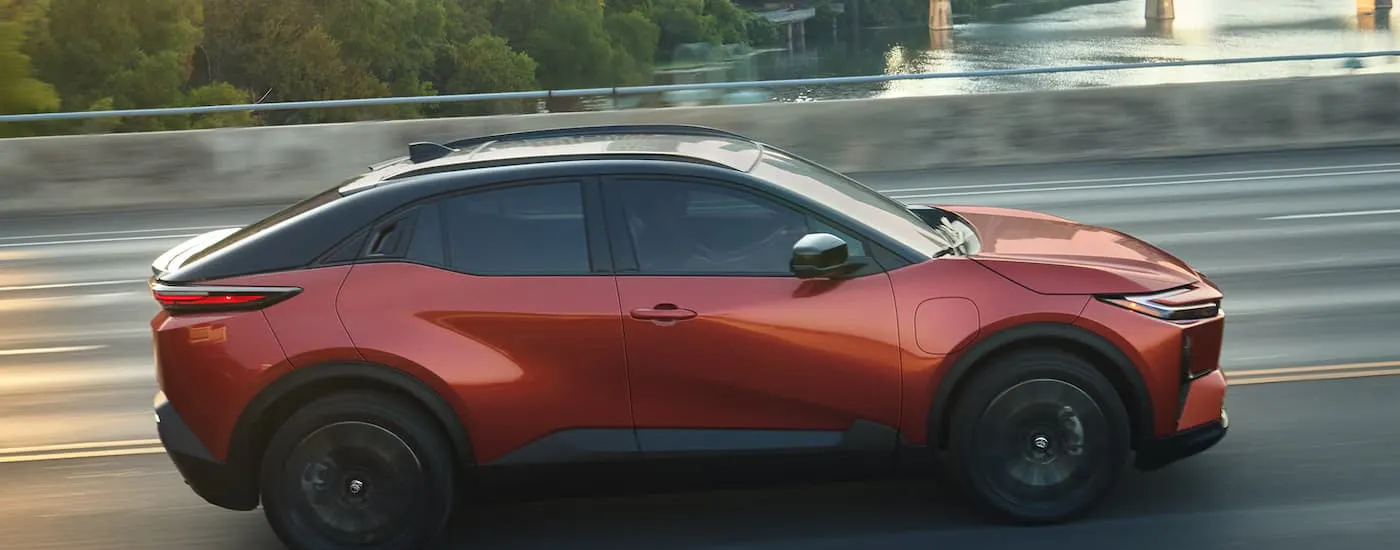 A red 2027 Toyota C-HR driving on a bridge