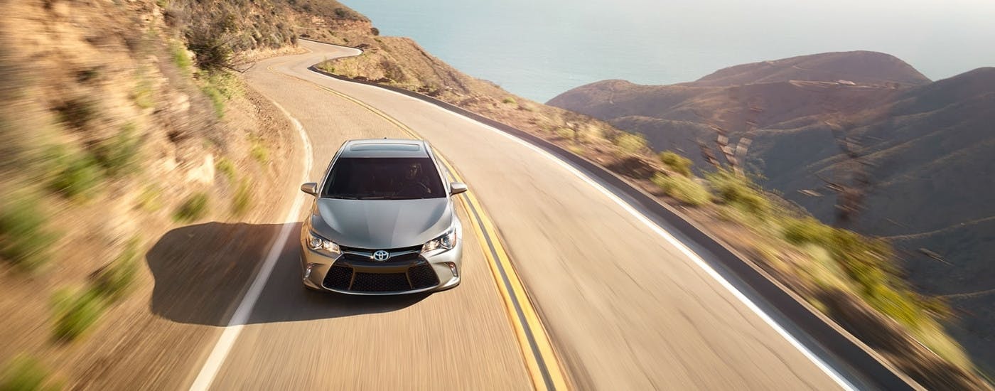 Silver 2015 Toyota Camry driving on a winding road