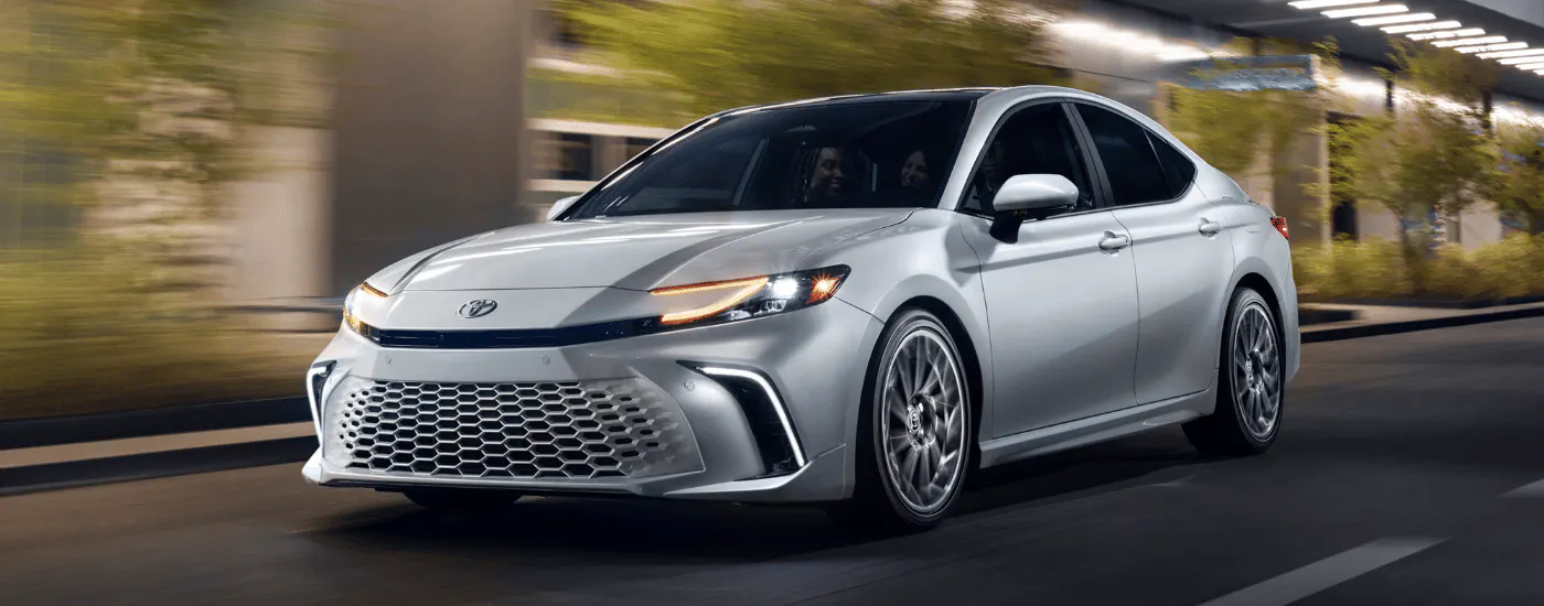White 2026 Toyota Camry driving under a highway overpass