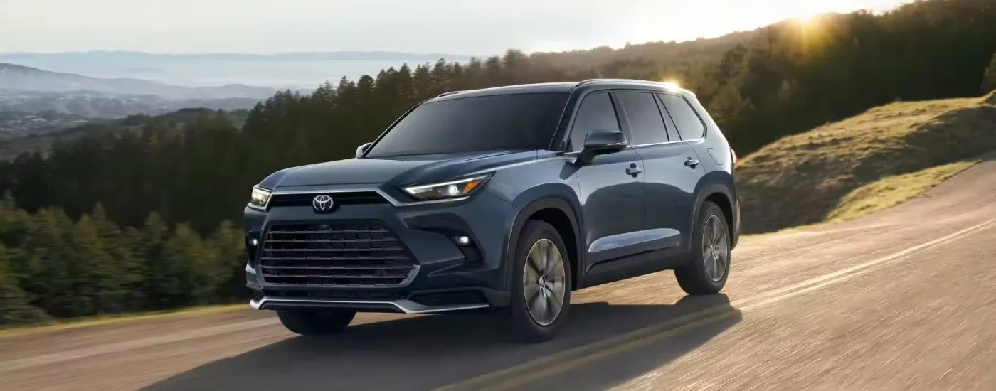 Blue 2024 Toyota Grand Highlander driving along an open road