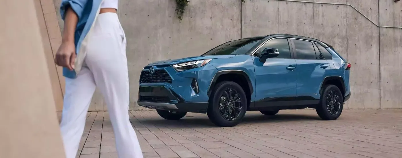 A person walking up to a blue 2023 Toyota RAV4