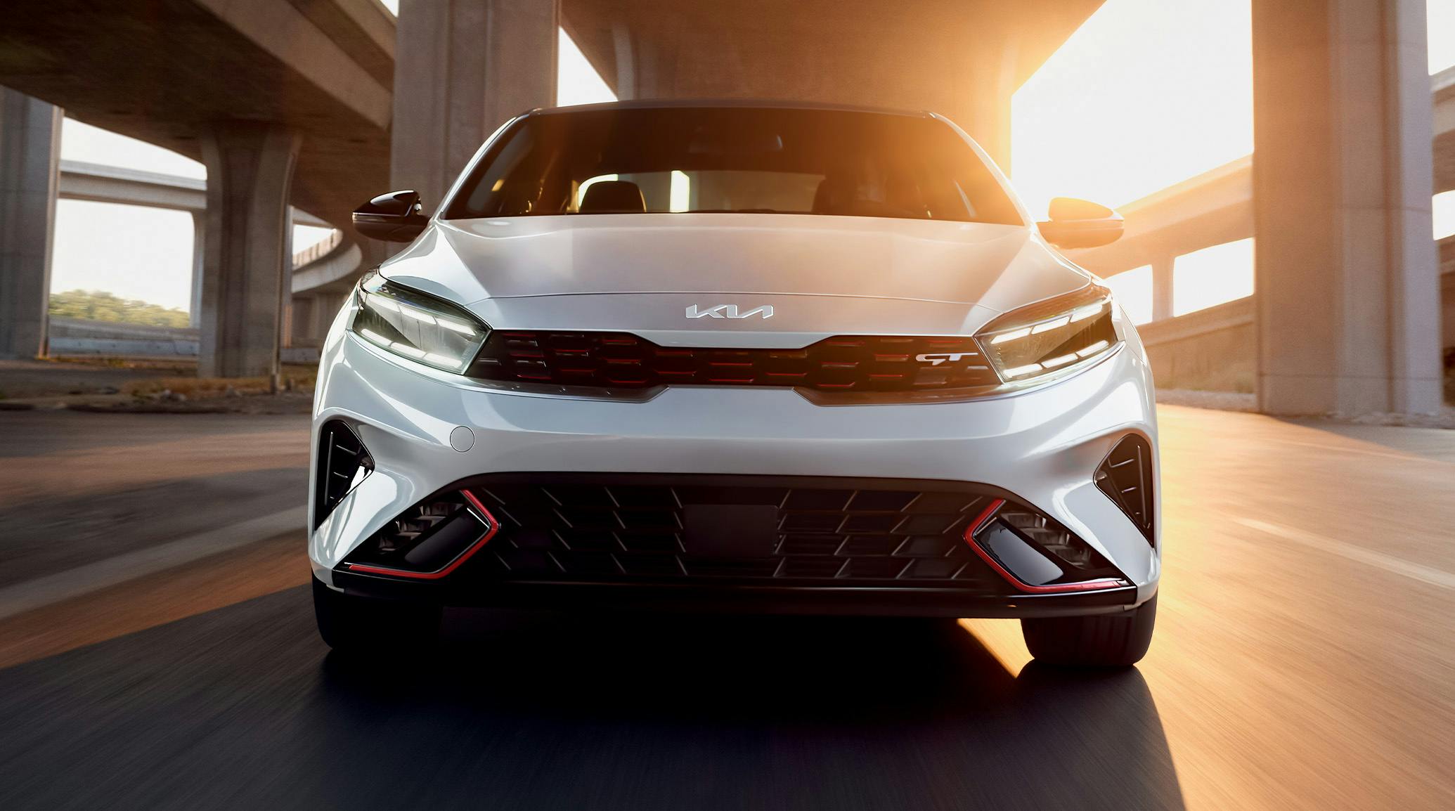 kia forte gt white driving under a bridge