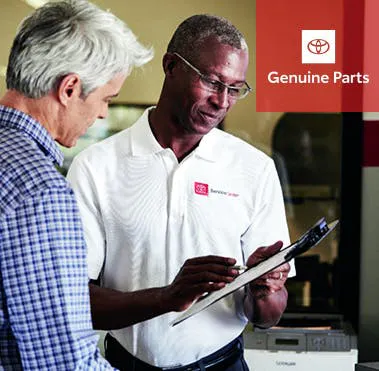 Helpful technician reviewing parts order on clipboard with customer.
