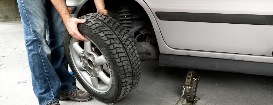 man rotating tire on car