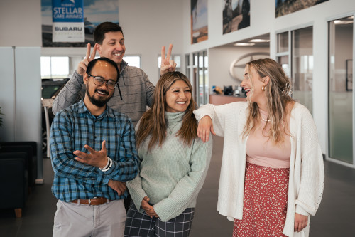 four adults smiling and laughing at dealership