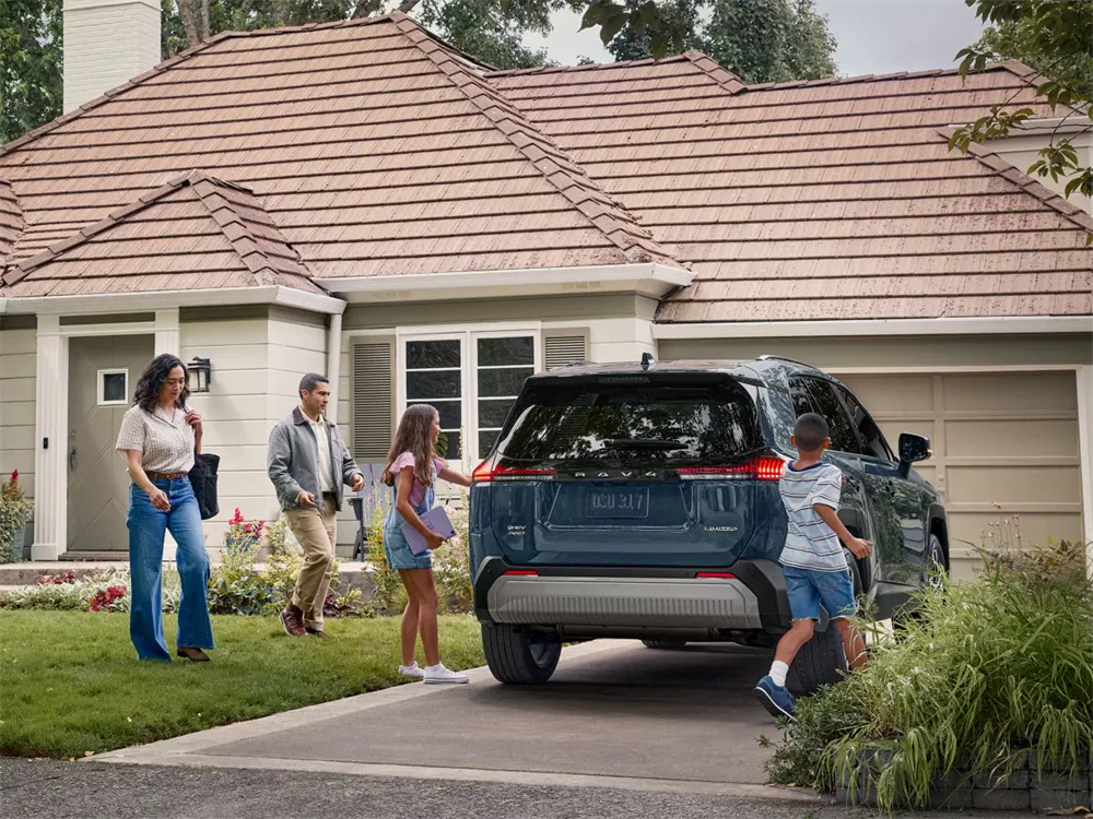 2026 Toyota RAV4 hybrid SUV parked in front of family garage with children and parents around it