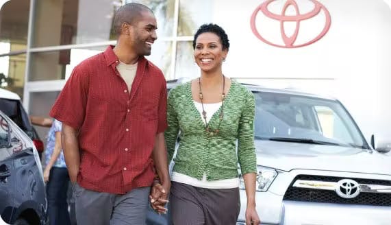 Happy couple walking through a Toyota Lot