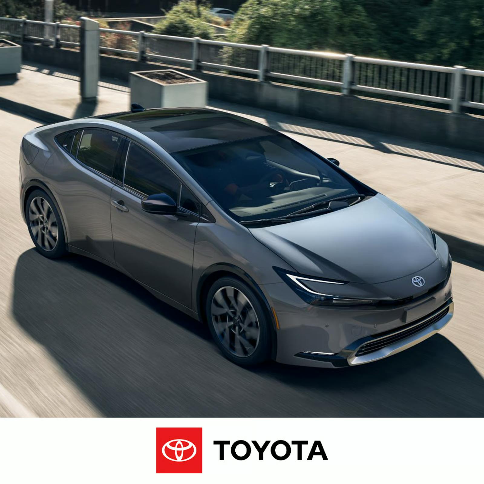 2024 Toyota Prius A Toyota Prius in motion driving over a bridge that has a wide sidewalk and guardrails