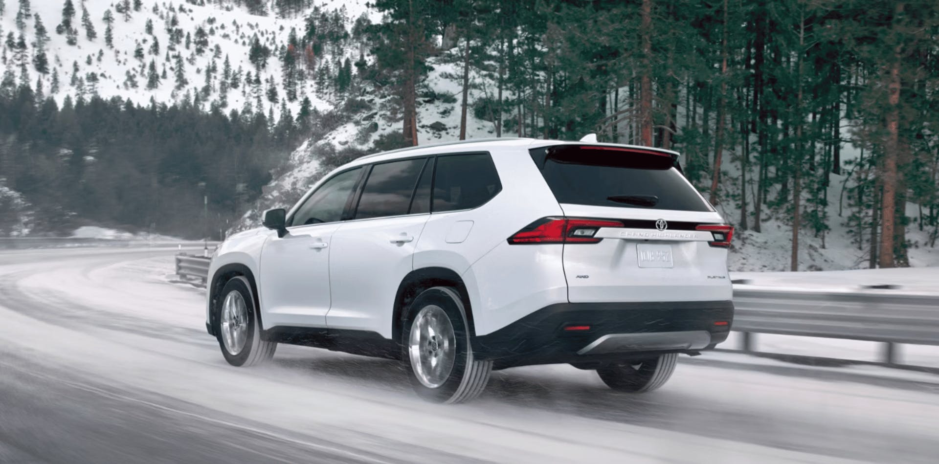 Toyota SUV navigates snow covered mountain road with pine trees