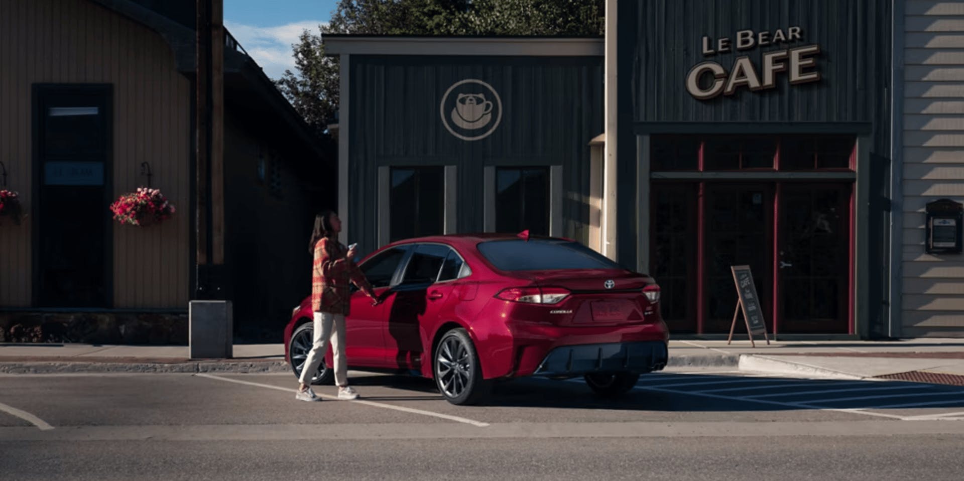 A women walking with a cup of coffee to car parked outside a shop