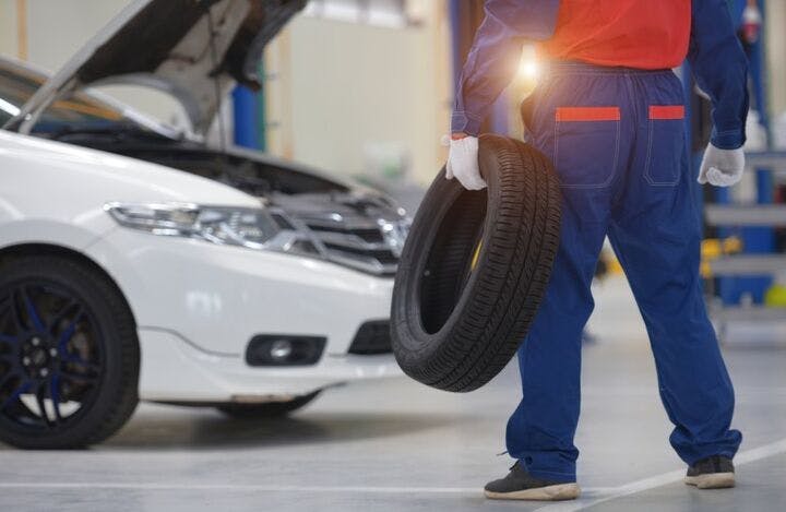 services_person_carrying_tire_standing_by_white_car_b services_person_carrying_tire_standing_by_white_car_b