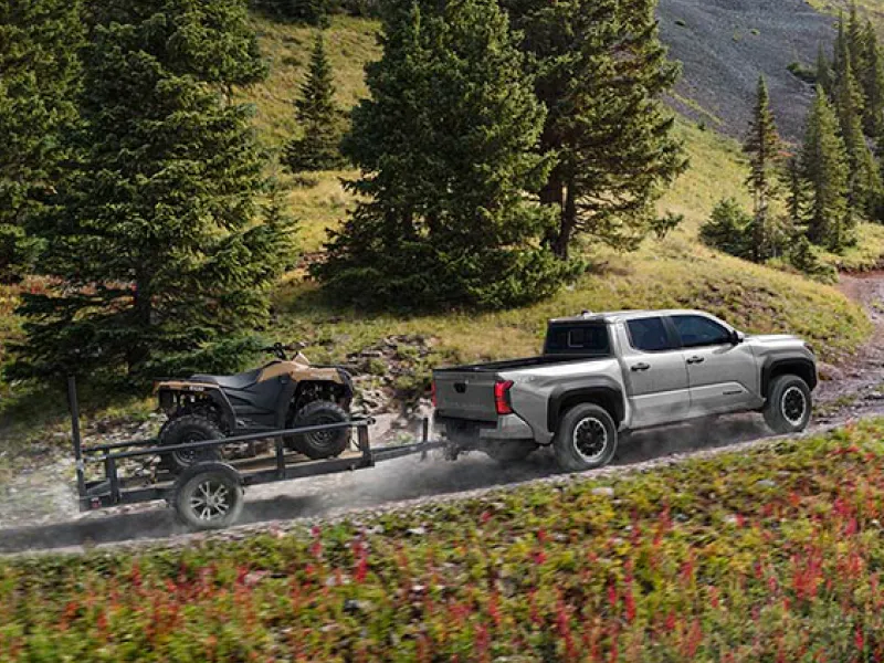 10_26_Steven_Toyota_SEO-Inset-1 Toyota Tacoma towing an ATV on a mountain trail.