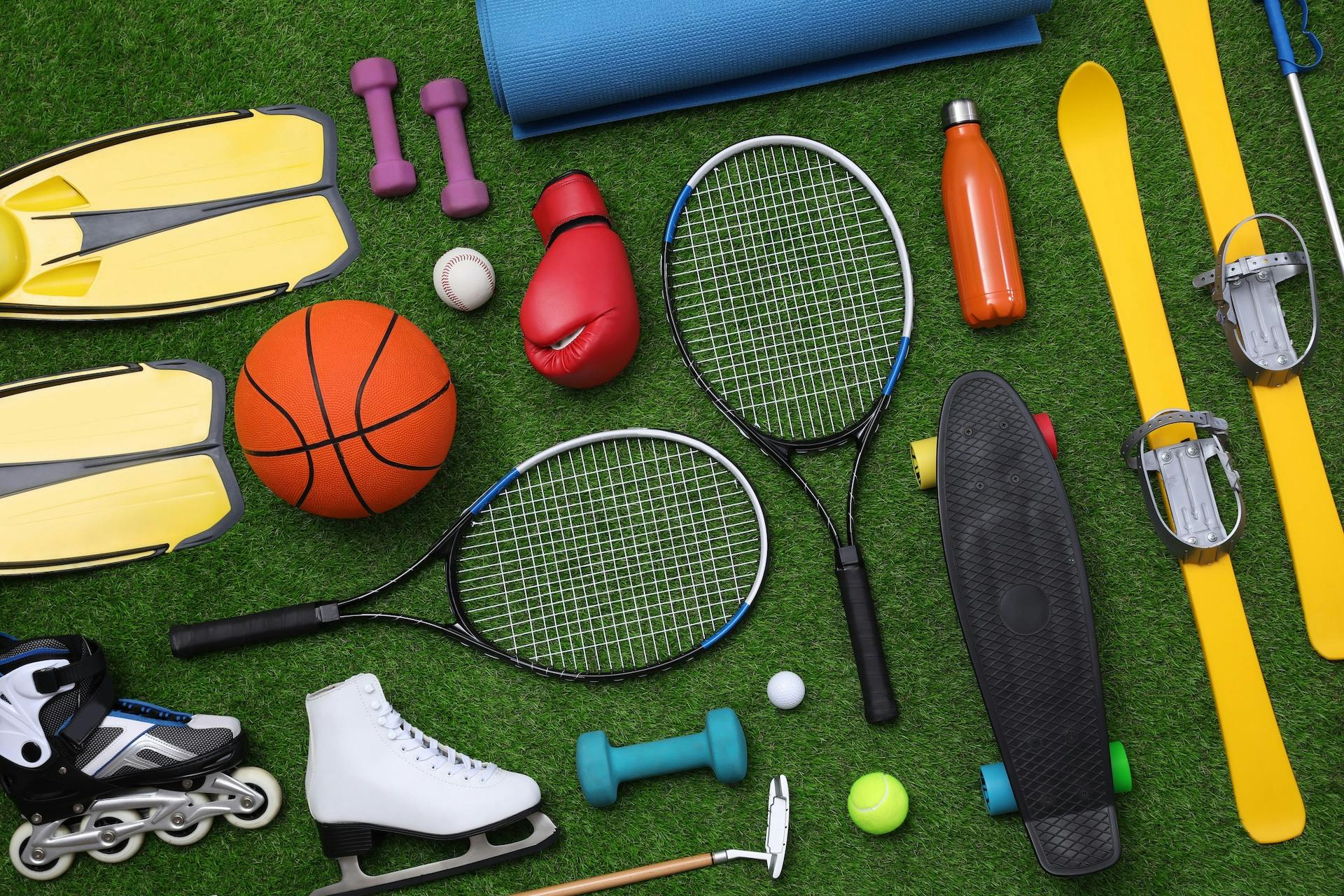 Different sport equipment on green grass, flat lay