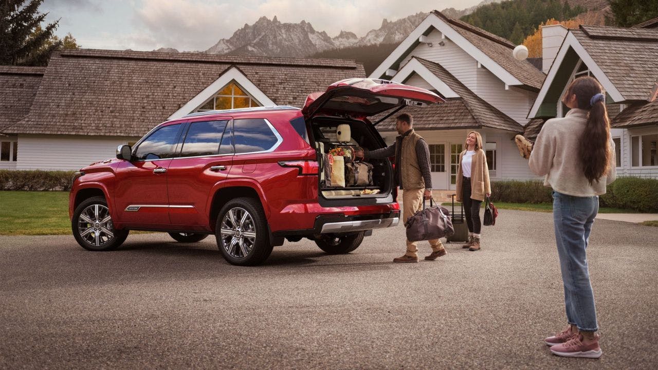 Family unloading luggage from a red SUV
