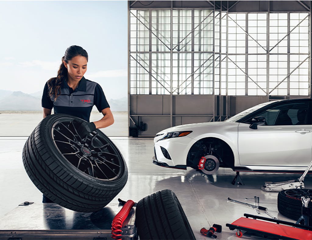 3 Main Benefits of Using OEM parts for your vehicle at Team Toyota of Glen Mills in Glen Mills, PA | Female mechanic holding new wheels with tires for the white Camry in the background