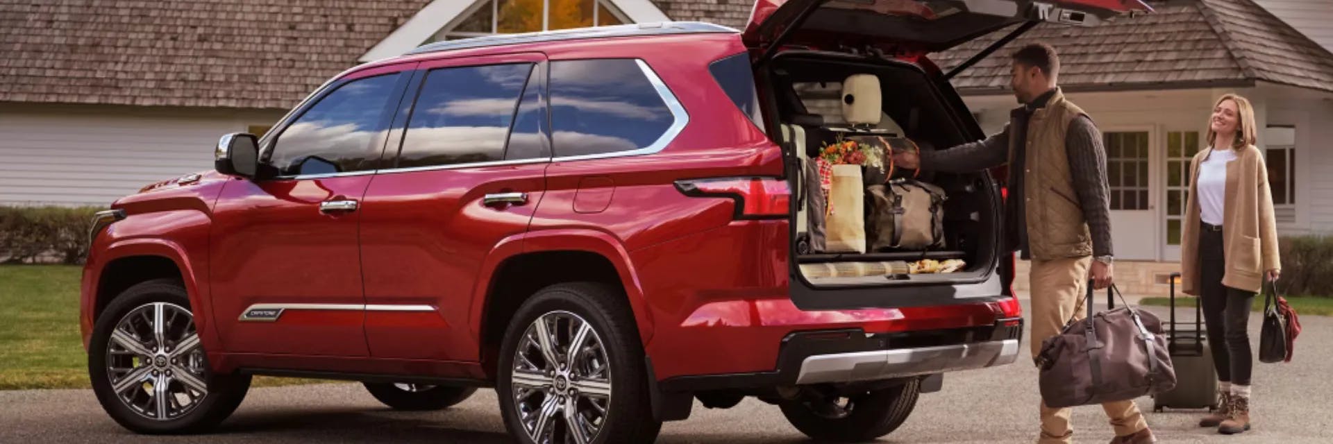 Couple unloading cargo from a Supersonic Red 2025 Sequoia Capstone