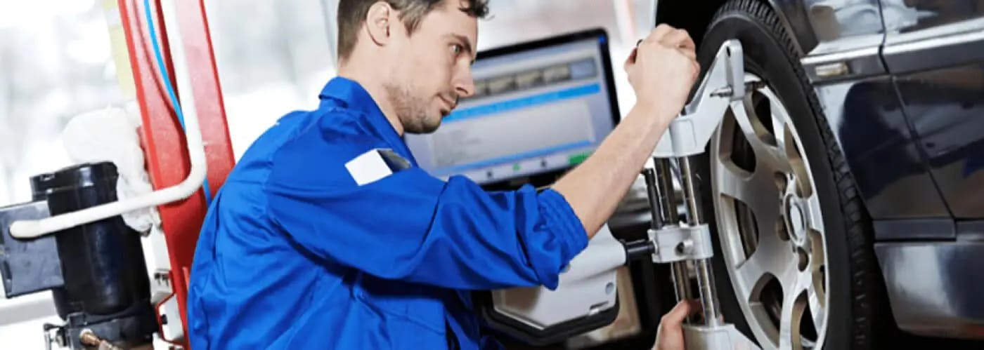 service technician performing wheel alignment