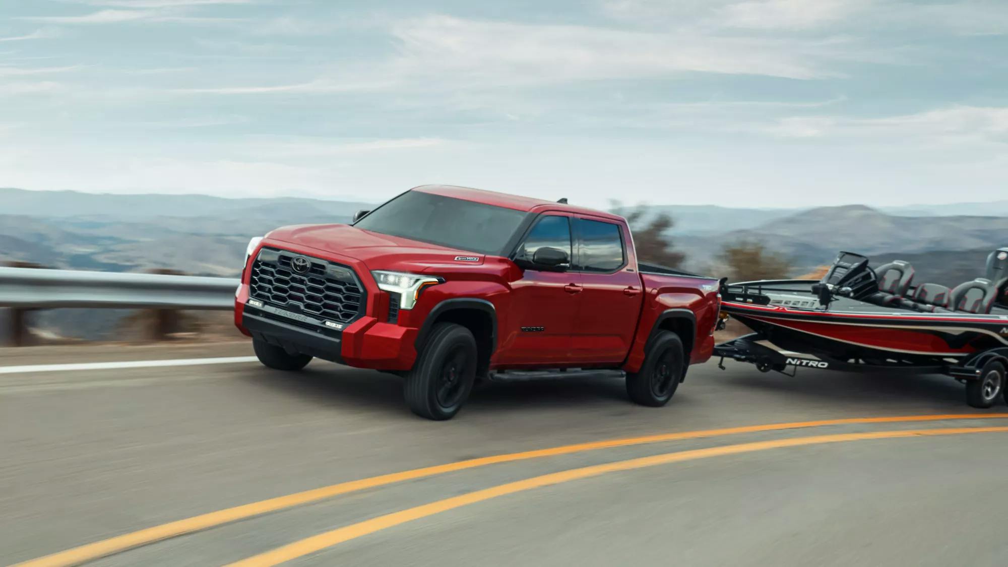 Toyota Tundra Red towing a boat up a hilly road