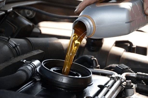 service tech pouring oil in vehicle