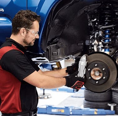service tech performing brake service on vehicle